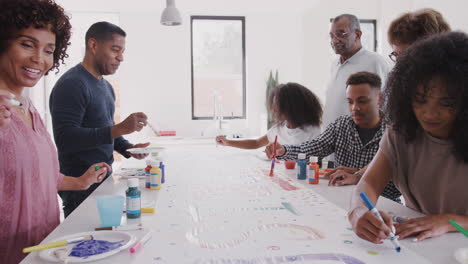 three generation black family preparing a sign for a surprise party in their kitchen, close up