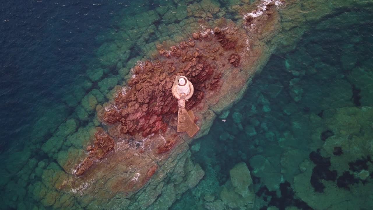 захватывающий дух вид сверху вниз на маяк на скалистом морском острове, уменьшение масштаба