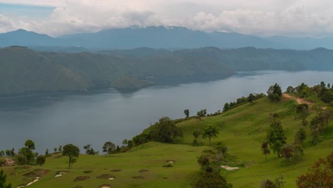 panoramic view of a large lake surrounded by green hills, with a golf course in the foreground