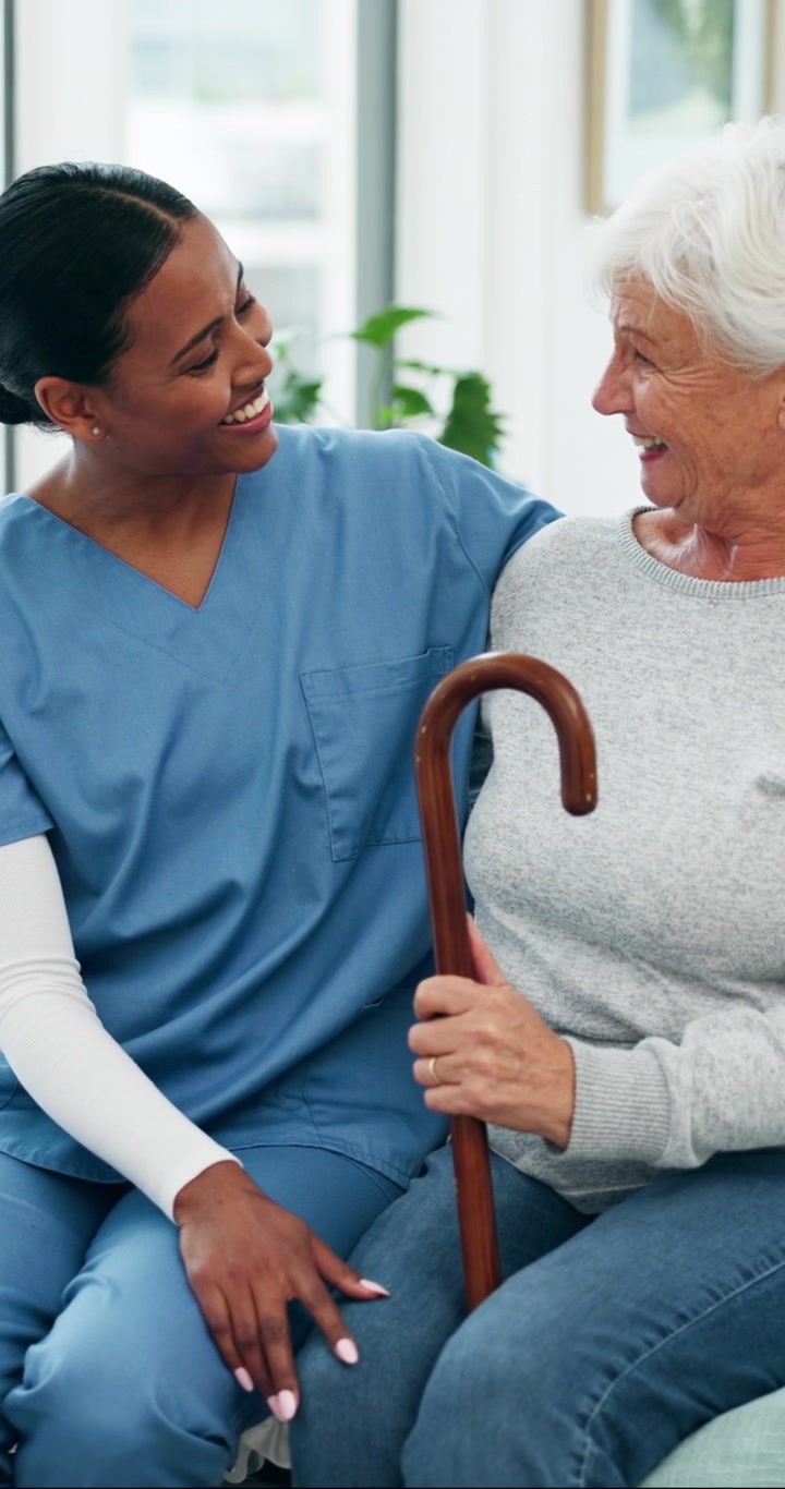 Young Caregiver Comforting Senior Woman with Walking Cane
