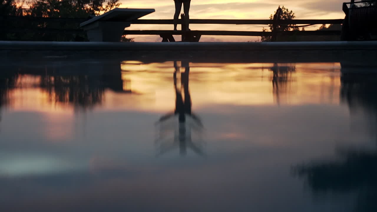 Woman Silhouetted at Sunset by a Pool