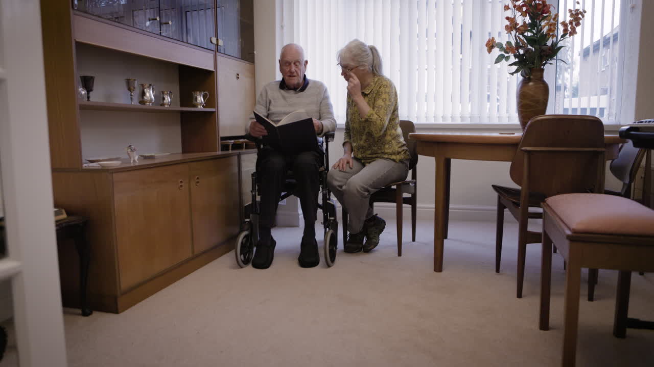 Elderly couple reading a book together in their home