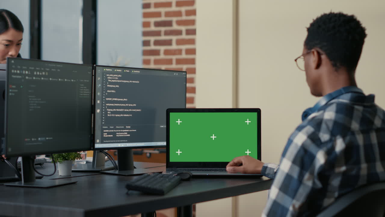 Database designer writing code using laptop with green screen chroma key mockup sitting at desk