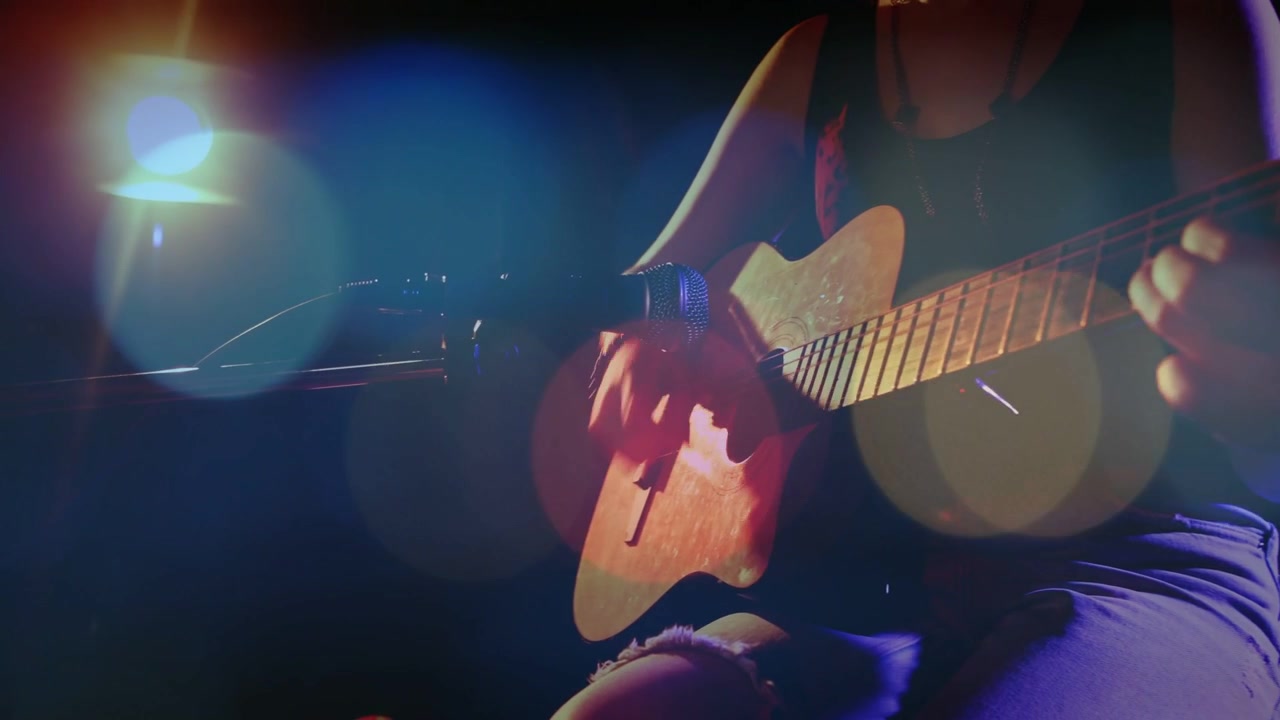 Panoramica della telecamera che rivela una musicista adolescente che suona la chitarra, con bokeh animato che accentua le mani per la musica