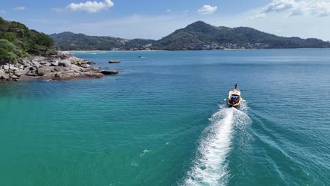 vista aérea de un barco de cola larga navegando a través de aguas claras de color turquesa cerca de phuket, tailandia, bajo la luz del día