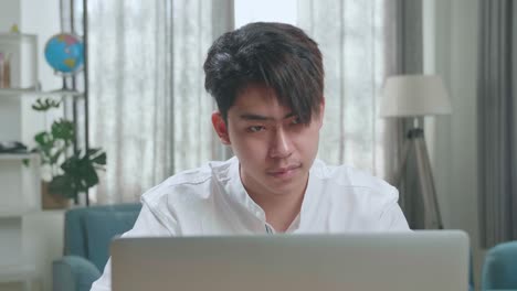 close up of a happy asian man student using computer to study online at home