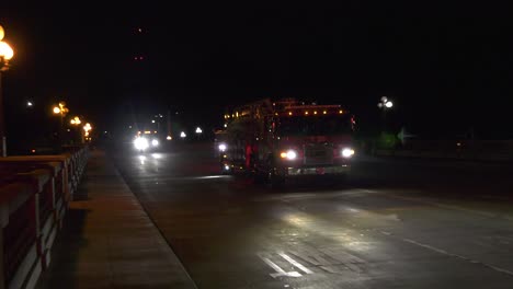fire trucks drive down dimly lit street