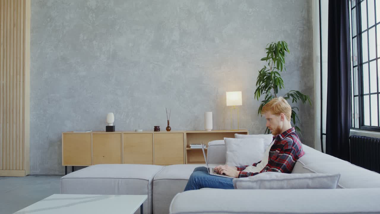 hombre trabajando en una computadora portátil en una sala de estar moderna