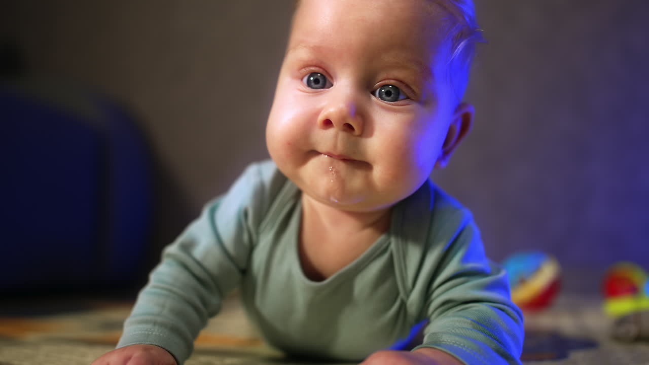 Lovely blond infant kid with big blue eyes. Baby boy with adorable cheeks looking around with interest. Close up.