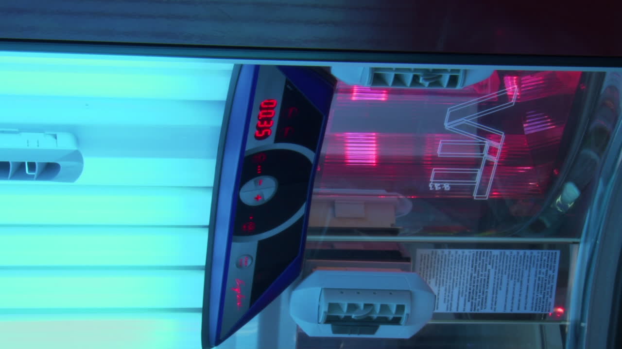 Pan left shot of open tanning bed switched on with bright blue lights