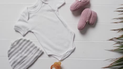 video of white baby grow, hat, dummy and pink booties with copy space on white background