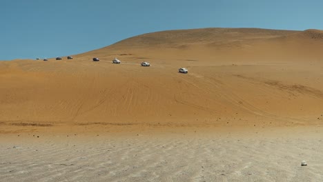 Reihe-Von-Lastwagen-In-Wohnwagen-Fahren-In-Sanddünen-Wüste-Ica-Peru-1080p-120fps