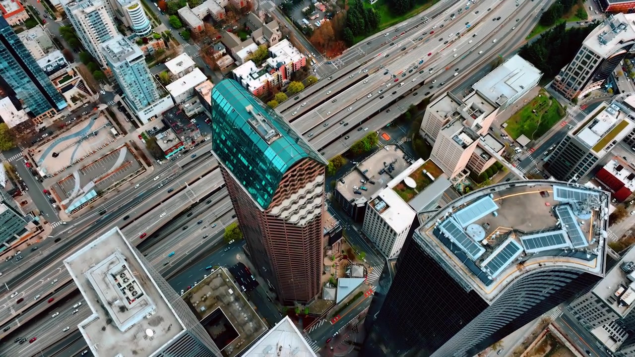 Voando sobre o topo dos arranha-céus no centro de Seattle, Washington, EUA. Vista da autoestrada de várias pistas com inúmeros veículos em movimento