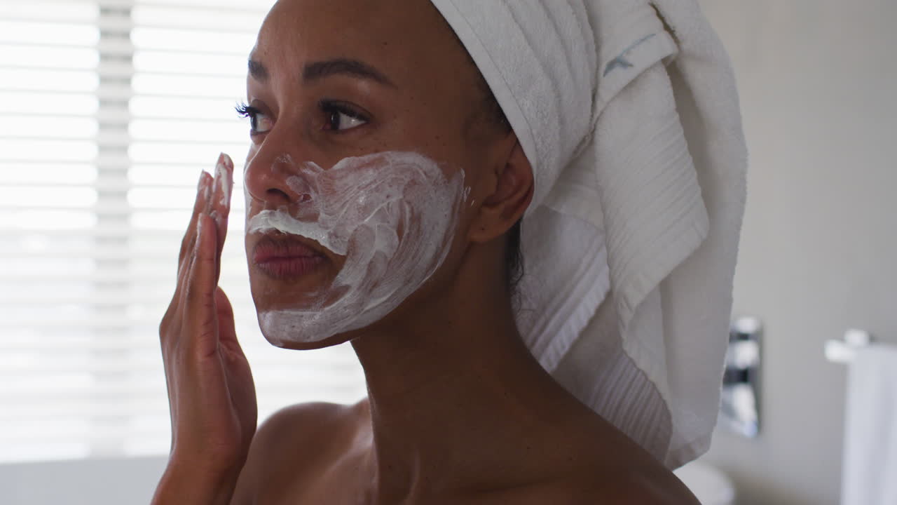 Close up of african american woman applying face mask in the bathroom