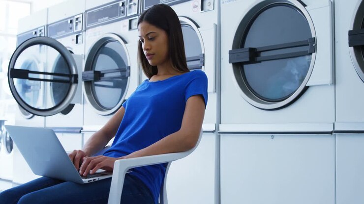 Woman using laptop at laundromat 4k