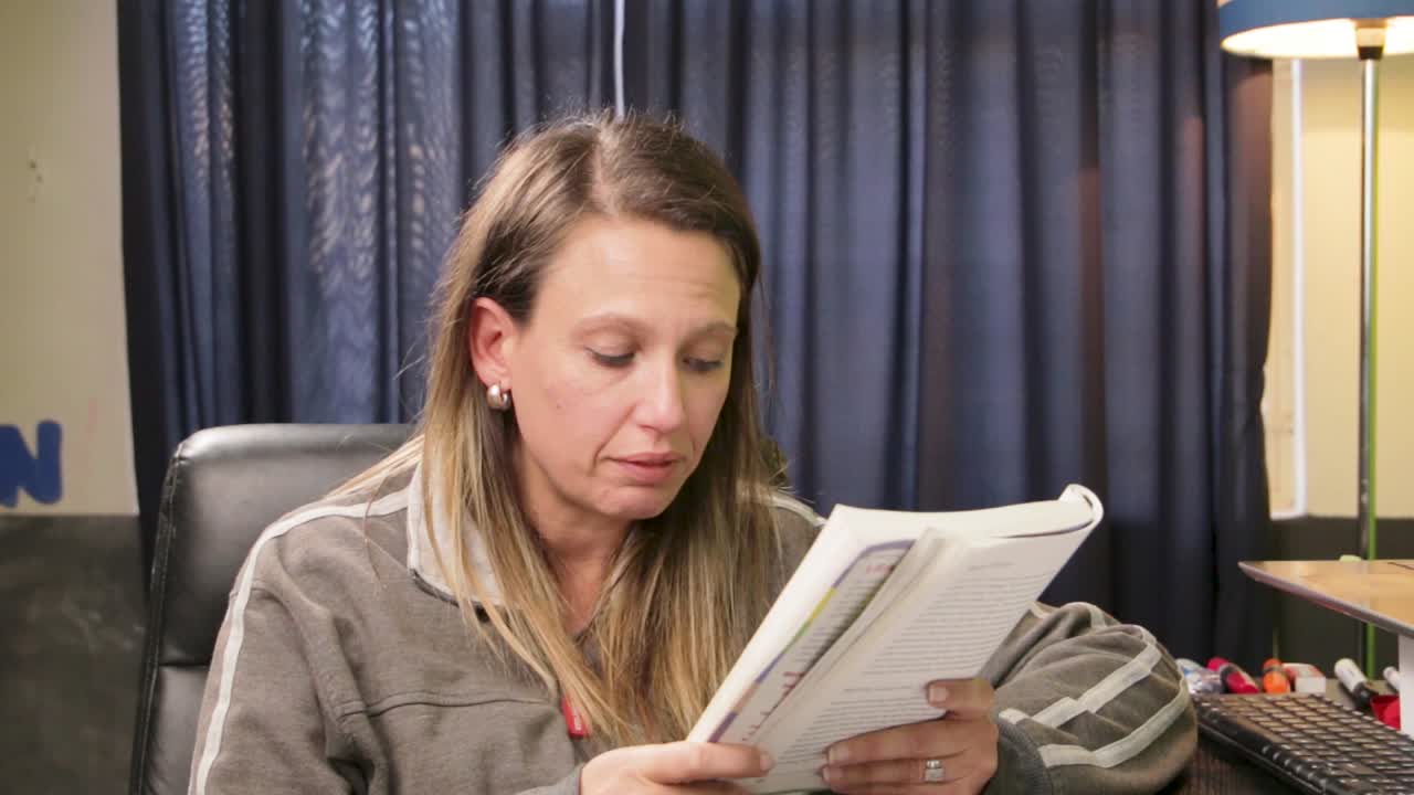 mujer leyendo un libro y explicando algo en cámara a una audiencia