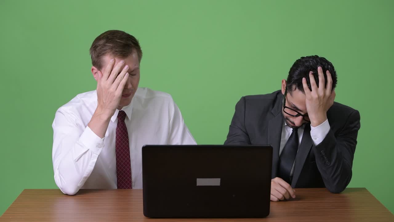 초록색 배경에서 함께 일하는 두 명의 젊은 다민족 사업가