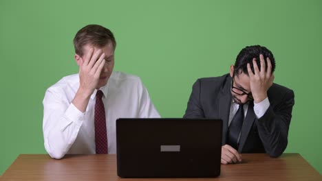 two young multi-ethnic businessmen working together against green background