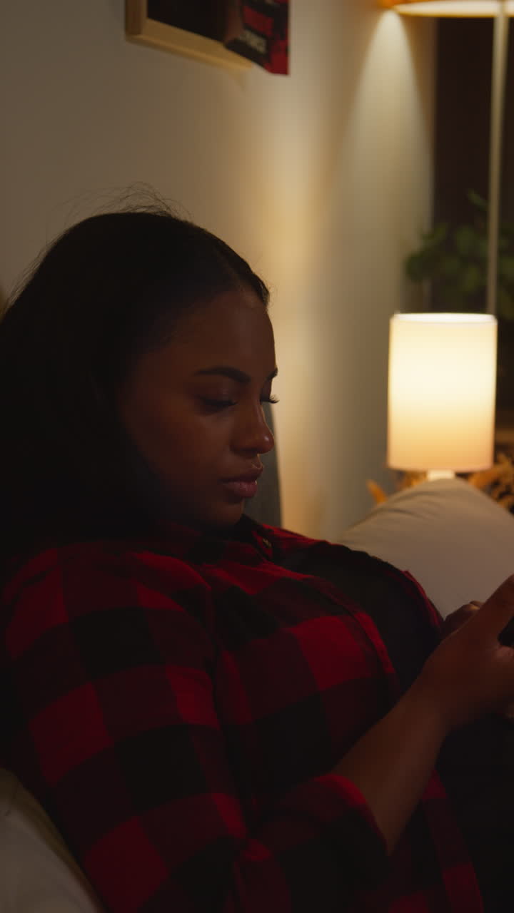 Donna che usa il telefono in una camera da letto buia