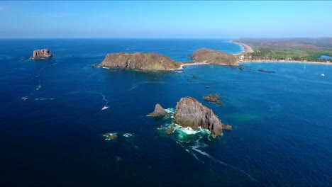 volo discendente in avanti su isole rocciose frastagliate con onde che si infrangono