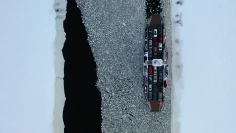 aerial view of a car ferry sailing through the ice of a frozen river