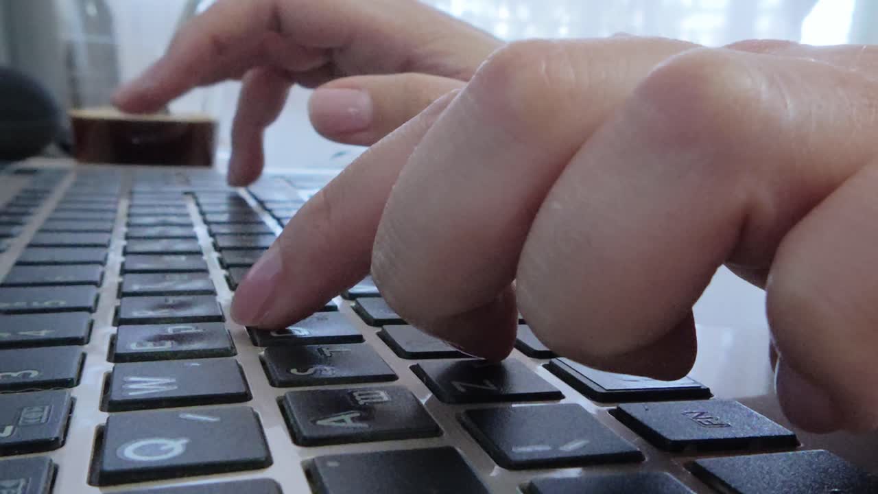 Side view of student's hands typing notes or completing assignments on a laptop.