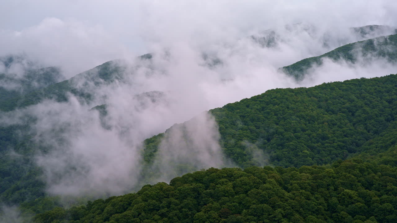 Drone captures a ghostly fog creeping across the mountain tops