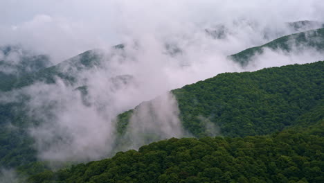 drone captures a ghostly fog creeping across the mountain tops