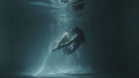 underwater gymnastics of a beautiful girl in a white dress