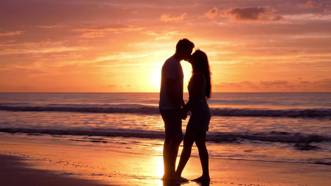 Una romantica silhouette al tramonto: una coppia che si abbraccia sulla spiaggia, creata dal caldo bagliore del sole che tramonta e si riflette sulle calme acque dell'oceano