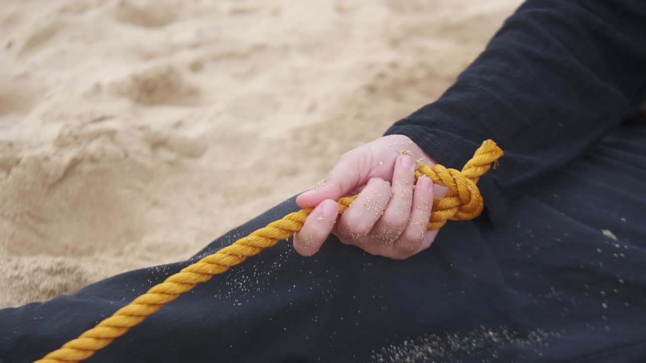 Dramatic close-up shot of young woman's hand gripping nylon rope as symbol of mental health struggles.