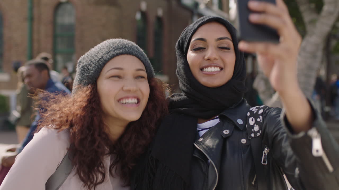 retrato de duas jovens amigas em close-up de namoradas multiétnicas posando fazendo caras tirando fotos selfie usando smartphone