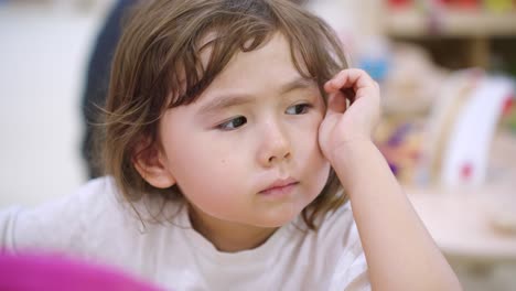 young ukrainian white toddler curiously using a drawing tablet, sitting with engaged expression in slow motion looking off into distance, close up