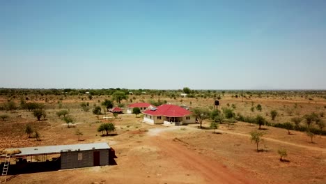 Aerial-view-zooming-away-from-a-Karamoja-village-house-on-a-sunny-day-in-Uganda,-Africa