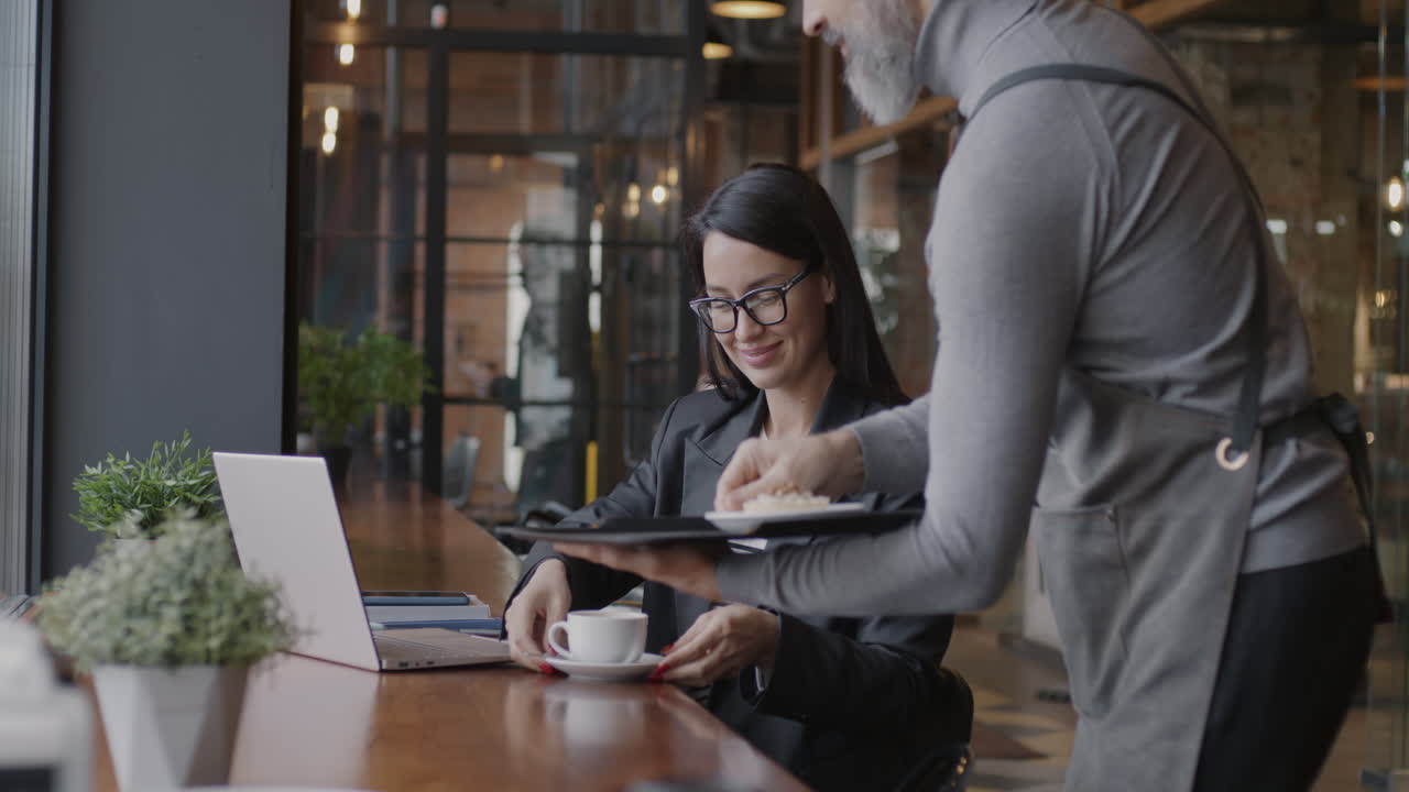 Businesswoman working in a cafe with a waiter