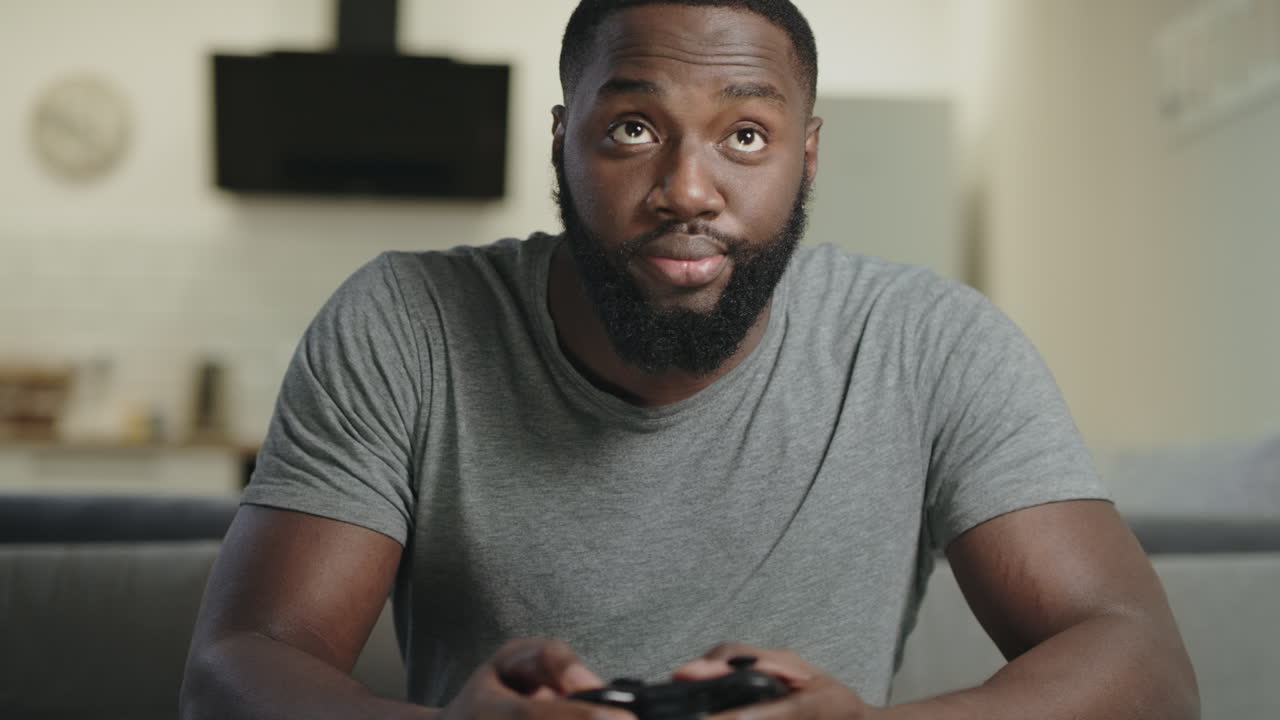 Black man playing video game at home. Upset guy sitting with play station.