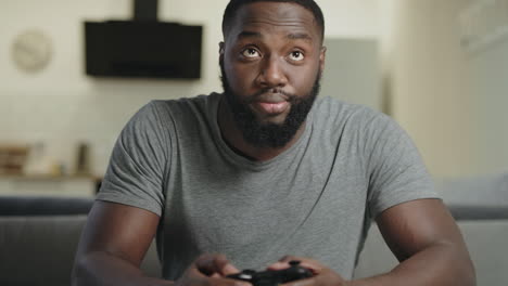 black man playing video game at home. upset guy sitting with play station.