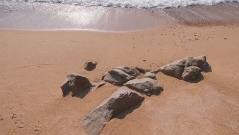 few rocks on a pale cream color beach in costa brava, spain