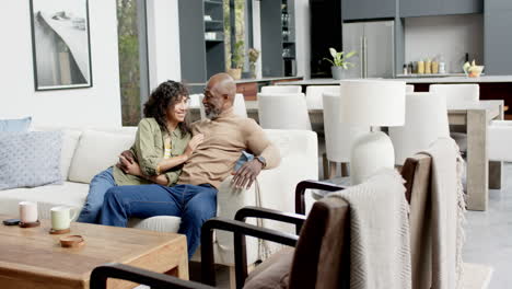 happy biracial couple embracing and watching tv at home, slow motion