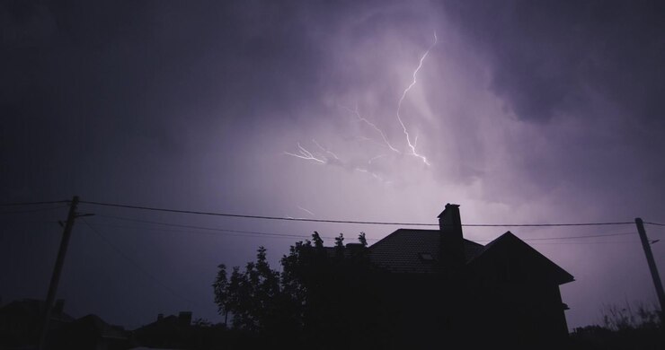 Lampi di fulmine sulla strada notturna illuminano la casa. Forte temporale con tuoni