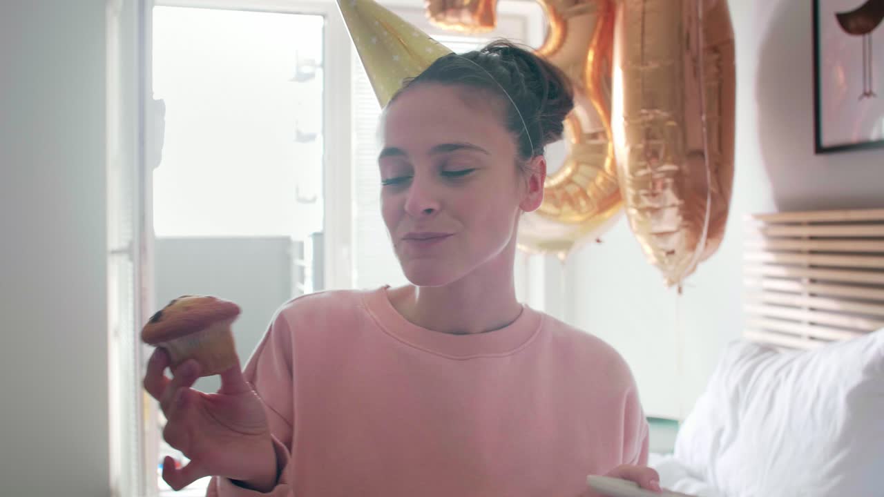 Donna che mangia una cupcake di compleanno in camera da letto.