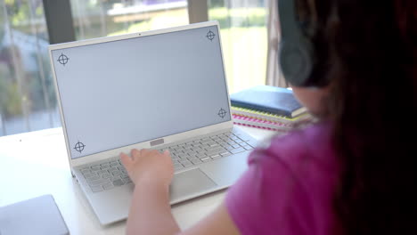 Biracial-girl-studies-at-home-on-her-laptop-with-copy-space