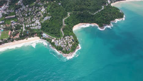 aerial view of tropical coastline with lush greenery and rocky peninsula surrounded by turquoise ocean waves