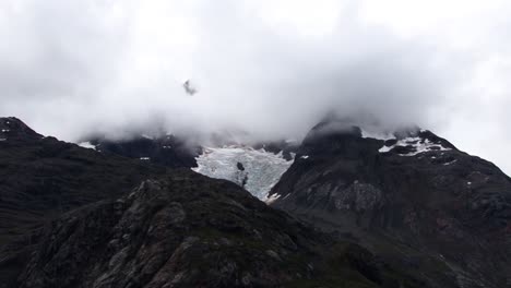 Fog-covering-a-snow-capped-mountain-in-Alaska,-Glacier-Bay-National-Park-and-Preserve