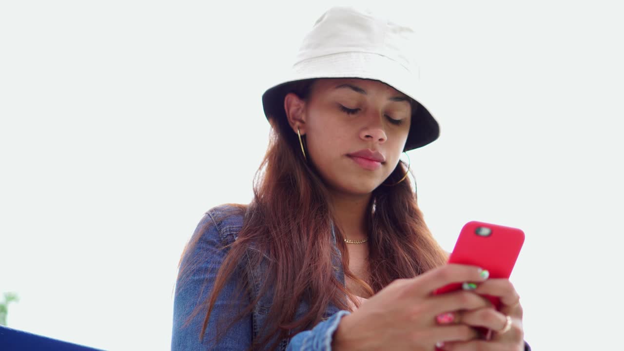 아름다운 젊은 여성이 거리에서 스마트폰으로 채팅하고 있습니다.