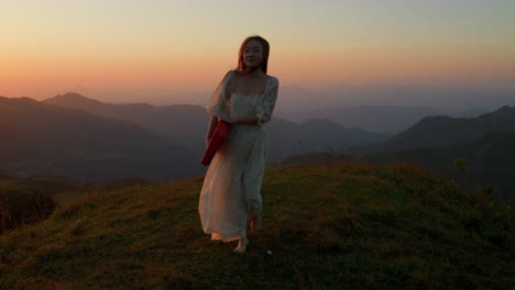 asiatic female musician artist walking barefoot in slow motion at sunset on a mountains path carrying piano keyboard