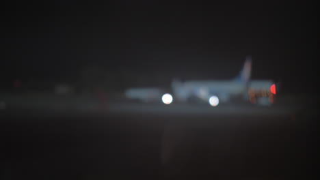 vista nocturna del avión y el tractor de remolque del avión en el aeropuerto desenfocado