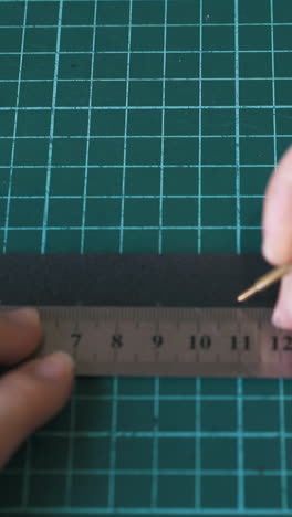 cu: skilled designer draws dots on black leather belt template with water soluble pen and metal ruler closeup
