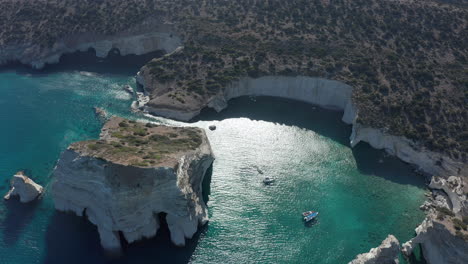 Aerial-Wide-Establishing-Shot-of-Tropical-Bay-in-Greece-with-White-Rocks-and-Boats-in-the-Ocean