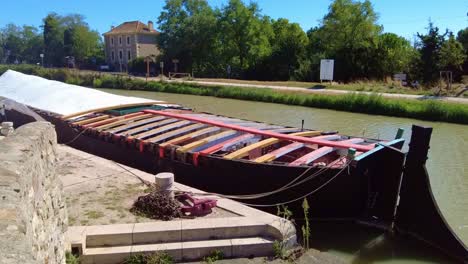 Canal-Du-Midi-France-brightly-coloured-barge-moored-at-Ventenal-En-Minervois-on-a-very-warm-summer-morning